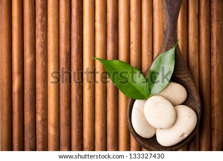 Spa stones in wooden spoon on wooden background.