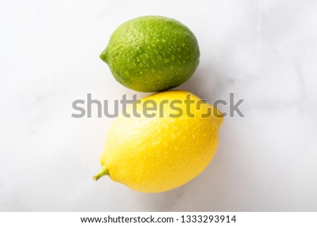 Yellow lemon and green lime on a white marble countertop