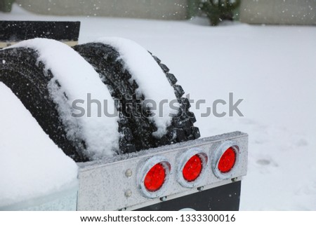 Truck tires and brake lights in a heavy snow storm.