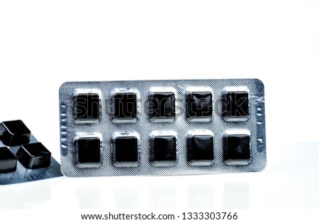 Medical pastille for relief cough, sore throat and throat irritation isolated on white background. Cough and colds drop. Black cough herbal extract lozenges in blister pack. Square candy or sweets.