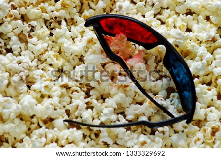 Popcorn for watching a movie in a Cup with 3D glasses on a red background.