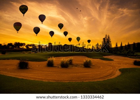 Silhouette hot air Balloons  flying above golf course scape at sunset time with  beautiful sunlight sky background