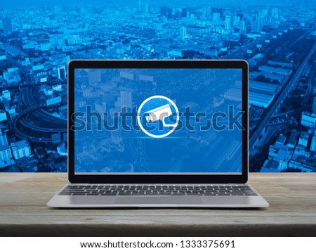 cctv camera flat icon with modern laptop computer on wooden table over city tower, street, expressway and skyscraper, Business security and safety online concept