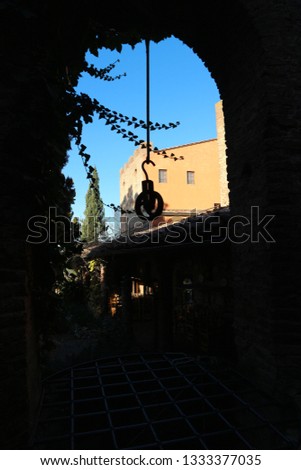 Old medieval well with chain and hook in Certaldo old town with old house and sky on the background