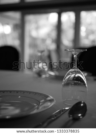 empty dish and wineglass on the dining table with fork , spoon and knife , in black and white photo style
