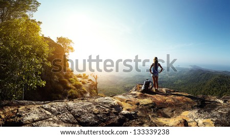 Hiker with backpack standing on top of a mountain and enjoying stunning valley view Royalty-Free Stock Photo #133339238