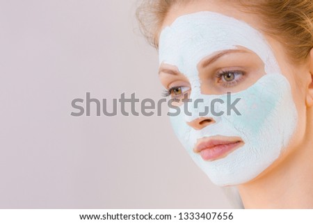 Young woman with white green mud mask on her face. Teen girl taking care of oily skin, cleaning the pores. Beauty treatment. Skincare.
