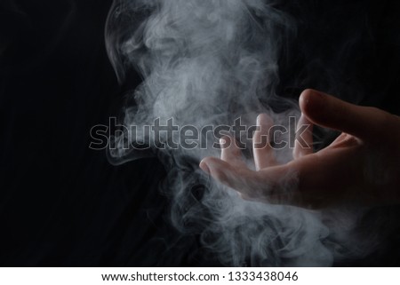 A hand gripping the intangibility of smoke like loss palm up fingers exposed with a drift of particles Royalty-Free Stock Photo #1333438046