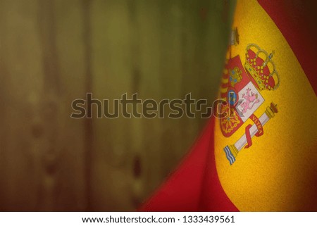 Spain hanging flag for honour of veterans day or memorial day on lime blurred natural wood wall background. Spain glory to the heroes of war concept.