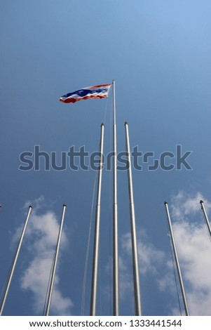 Thailand National Flag Flying on Flagpole Against Blue Sky and Clouds Background