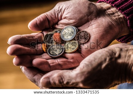 Pensioner man holding in hands euro coins. Theme of low pensions. Royalty-Free Stock Photo #1333471535