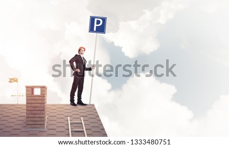 Businessman on house top holding car parking board and viewing city. Mixed media