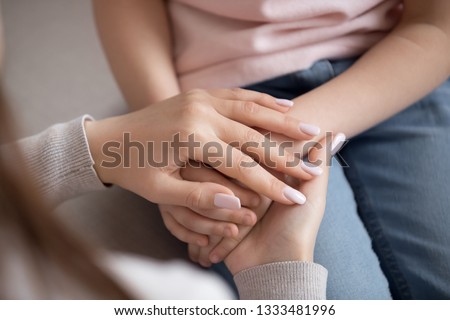 Adult woman mother holding hands of little child daughter love charity support concept, parent children protection, kid adoption, foster care, family trust connection hope and donation, close up view Royalty-Free Stock Photo #1333481996