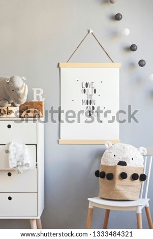 Scandinavian child room with mock up poster frame on the grey wall, white commode, teddy bear and toys. Cute modern interior of playroom with white walls, wooden accessories and toys.