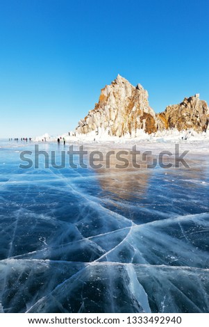 Lake Baikal on a sunny winter day. Numerous tourists come to Olkhon Island, walking on the ice and taking pictures of the famous Shamanka Rock - the natural landmark of the lake