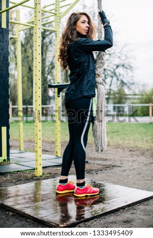 Young female athlete wearing sport jacket and tights preparing for rope training in the morning