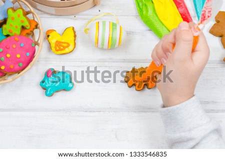 Child hands decorating honemade gingerbread with icing sugar using a pipping bag. Easter Treats. Handmade cookies, standing on the table. series of step by step photos. Royalty-Free Stock Photo #1333546835