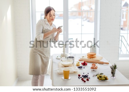 attractive girl taking picture of ingredients for cake. close up photo. pleasant girl sending photos to her friends while working in the kitchen. copy space