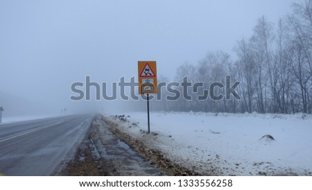 Warning sign in winter on a misty morning on the highway