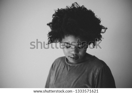 High ISO Black and White Studio Photos of A Young African Woman against a white wall with a big afro.