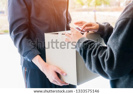 Online shopping / ecommerce delivery service concept : Delivery package to Asian Customer signature smartphone for receive cardboard packages from postman deliver and payment terminal destination.
