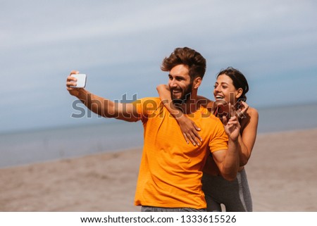 Young sports couple taking selfie on the beach