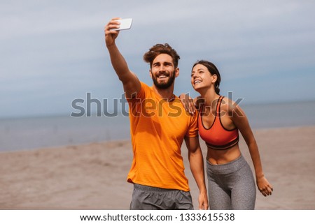 Young sports couple taking selfie on the beach