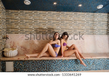 close up photo of two beautiful women wearing swinsuit relaxing in hamam