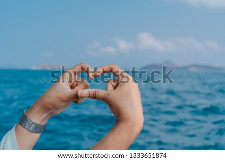 Hands in the shape of heart against the  over the sea. Hands forming a heart shape. Travel concept.