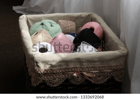 Balls of yarn in a basket with a border by the window