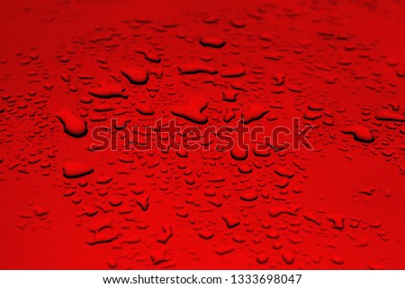 Raindrops lie on a metallic red surface of gray color. Abstract picture for background and design. The drops of water lie on the surface.
