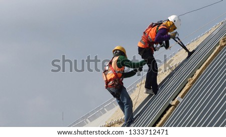 construction worker wearing harness helmet sunglass and sun protection mask to metal sheet in stalltion on high places Royalty-Free Stock Photo #1333712471