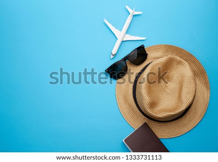 Travel concept before retirement, Flat lay of straw hat, passport with money, plane model and sunglasses, on blue background, with copy space.