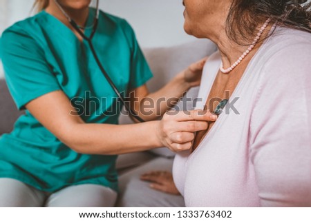 Health visitor and a senior woman during home visit. Medicine, age, support, health care and people concept - doctor or nurse with stethoscope visiting senior woman and checking her heartbeat 
