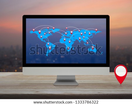 Map pin location button with connection line and world map on computer monitor screen on wooden table over blur of cityscape on warm light sundown, Elements of this image furnished by NASA