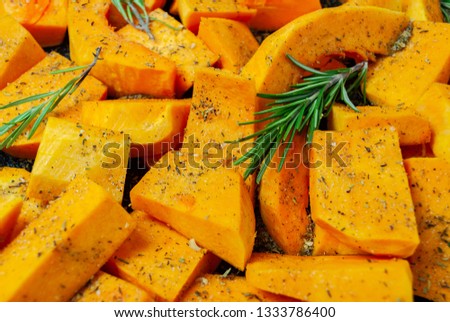 Sliced pumpkin Butternut squash, sprinkled with seasoning. With sprigs of rosemary. For baking. Macro picture.