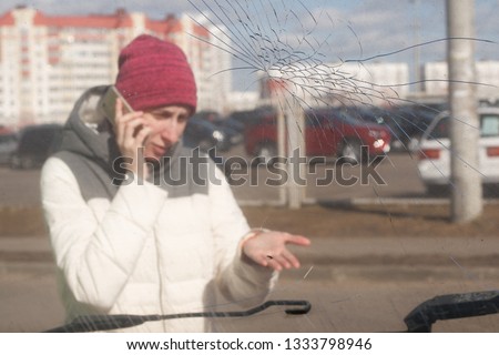 Adult upset driver young woman calling on the phone in front of automobile crash car collision accident in city road 
