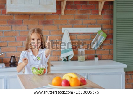 Teen girl eats salad and shows cool / copy space.