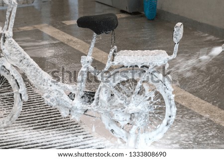 Electric bicycle in foam in a car wash. Washing a bike with a jet of foam. Preparation for the spring season