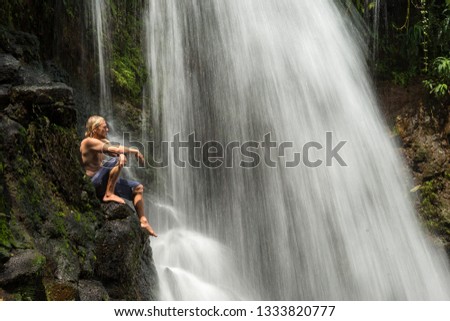 Athlete traveler enjoys of the waterfall with clear water among the jungle of Mauritius