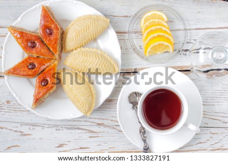 Traditional Azerbaijan holiday Novruz cookies baklava on white plate on the white background with nuts and shakarbura,a cup of tea,lemon,kata,mutaki,flat lay,top view,space for copy