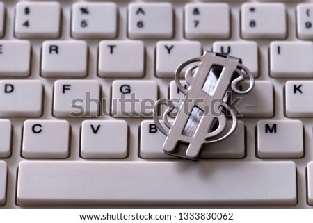 Metal clip waiting to be denominated in the form of the US dollar. Closeup of a part of a white computer keyboard. Design of money and information technology. Background finance and online investment.