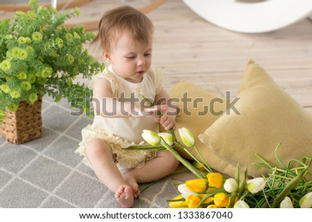 a little girl in a light dress among tulips and plants