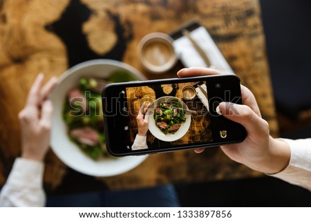 Woman taking a picture of her lunch while sitting at the cafe indoors