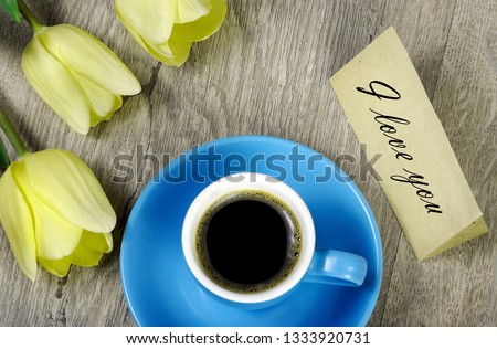 bouquet and a cup of coffee. tulips and a cup of coffee. coffee and a note i love you. inscription i love you. top view