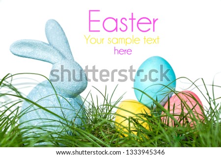 Easter bunny sitting on a meadow with colorful painted Easter eggs