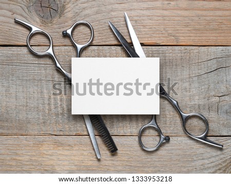 Vintage hairdressing scissors and blank business card on wooden table