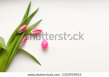 Bouquet of pink three tulips with green leaves with one egg on a white background. Beautiful flower in the spring season. Top view of empty space