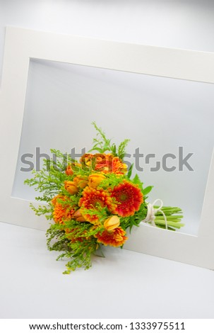 Bouquet of fresh orange gerbera flowers and tulips framed in a white cardboard mat or picture framing, isolated on a white background 