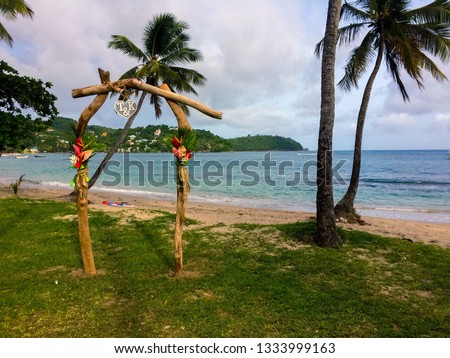 A driftwood altar stands on Rudy John beach in Laborie, Saint Lucia with palm trees and the Caribbean Sea in the background. Royalty-Free Stock Photo #1333999163